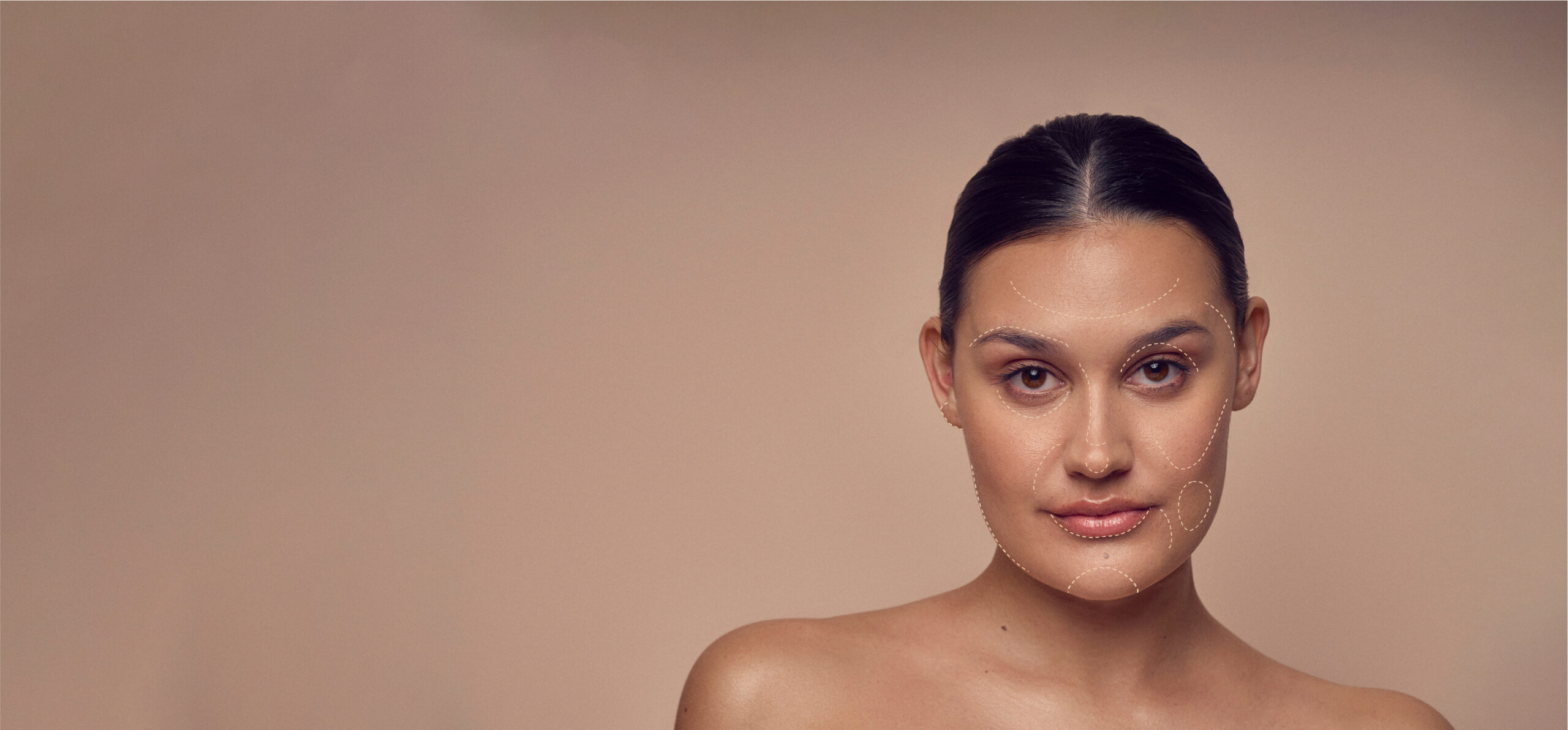 A woman with dark hair pulled back poses against a beige background. Subtle lines trace facial contours on her skin, suggesting a focus on skincare or beauty treatments. She has a calm expression and bare shoulders.
